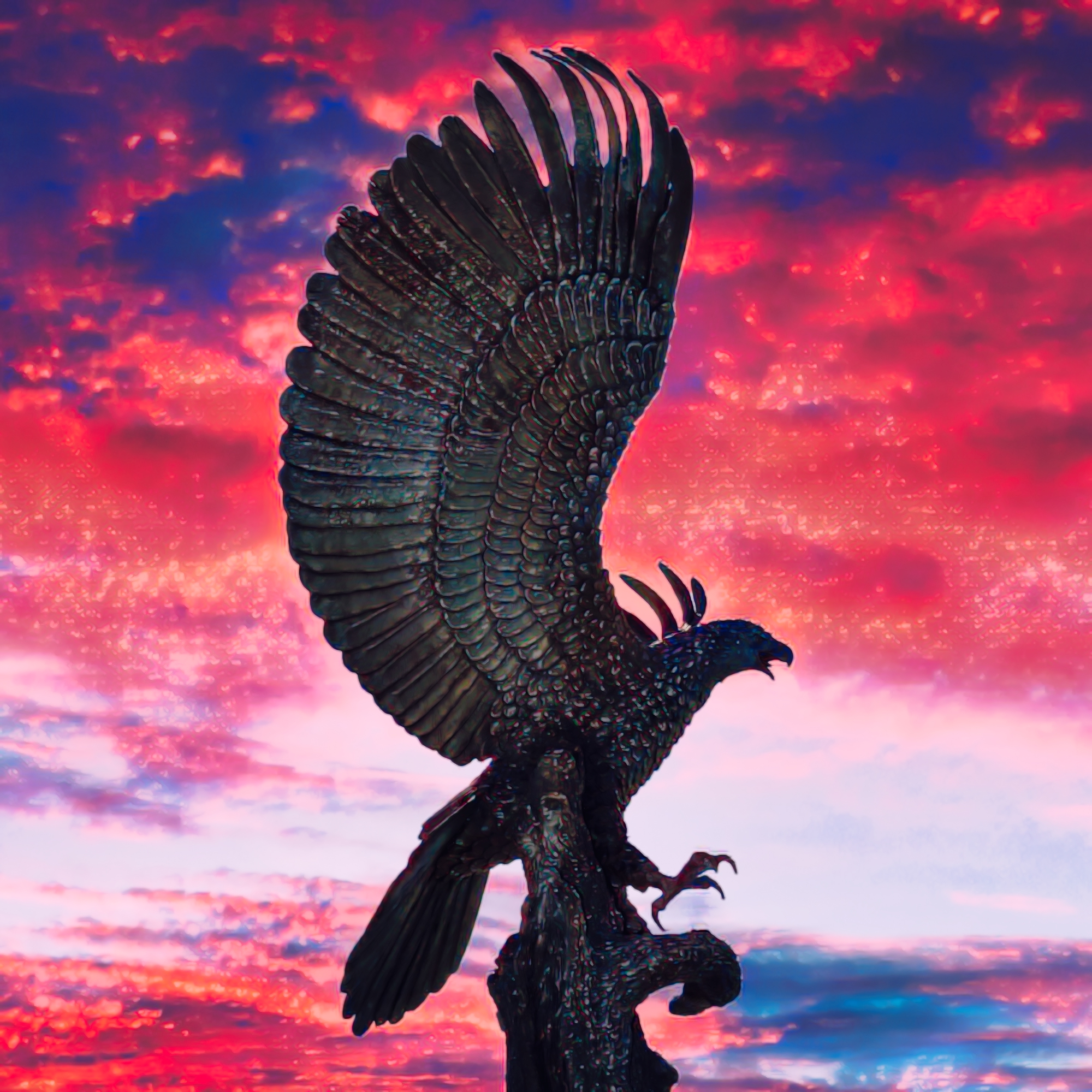 きれいな空と夕日の中の鳥の彫刻